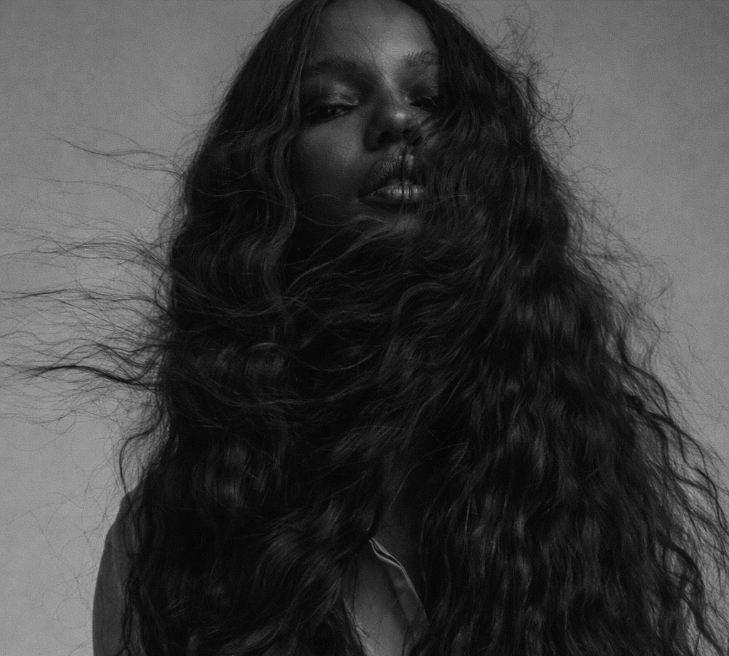 Black and white portrait of a person with wavy hair against a plain background